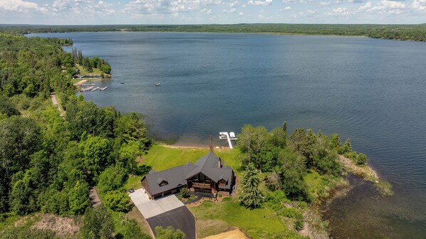 Un chalet au bord du lac, doté d’un quai, et entouré d’une forêt dense.