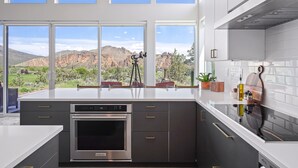 A modern kitchen with a large island, built-in oven, and a view of mountains through large windows. - Spectacular Smith Rock Views on 5 Acres - Quiet and Modern w/ King Beds (Terrebonne)