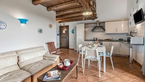 Una sala de estar con un sofá, una mesa de centro con revistas, y un comedor con una mesa y sillas.