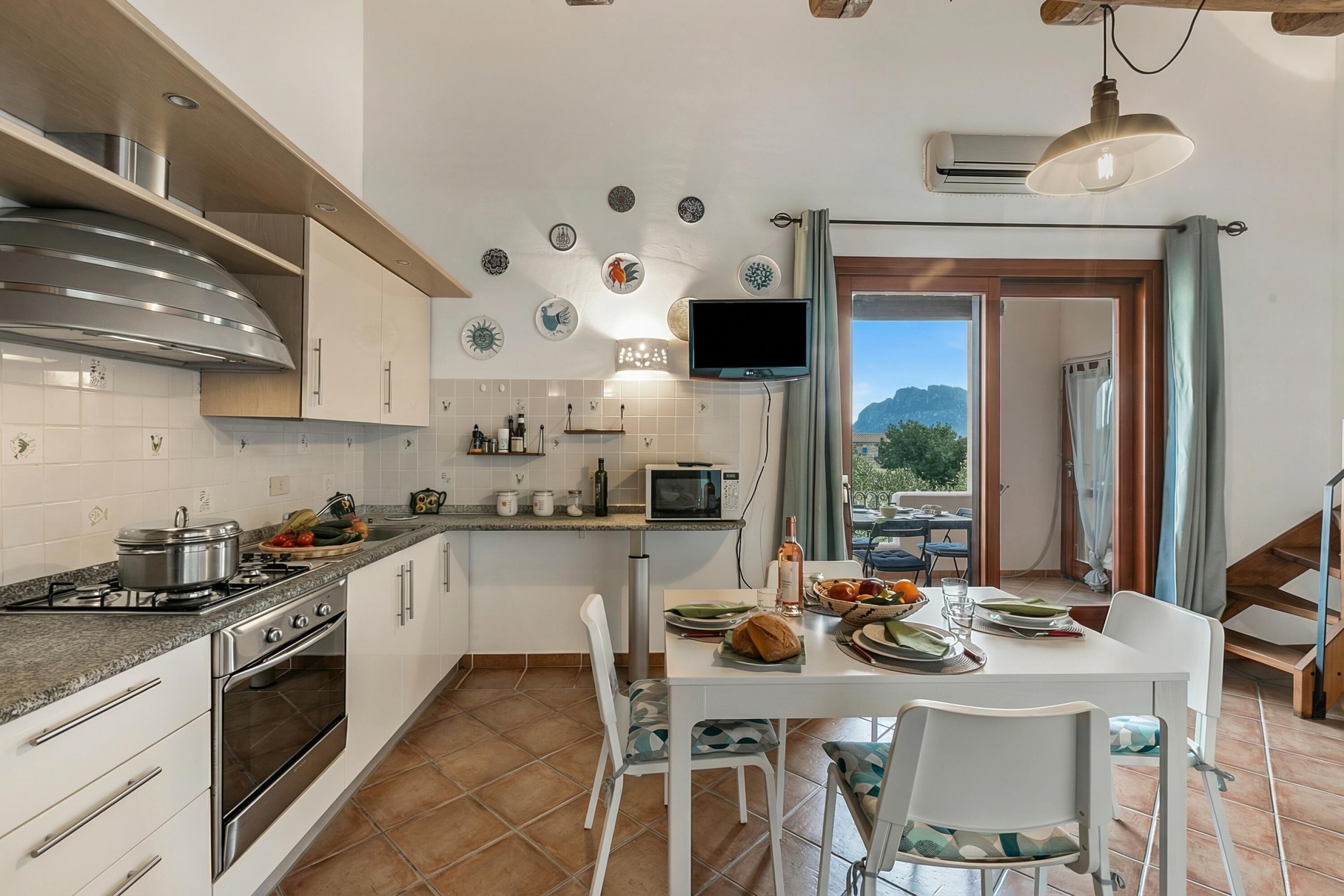 Una cocina con estufa, microondas y mesa de comedor dispuesta con platos y vasos.