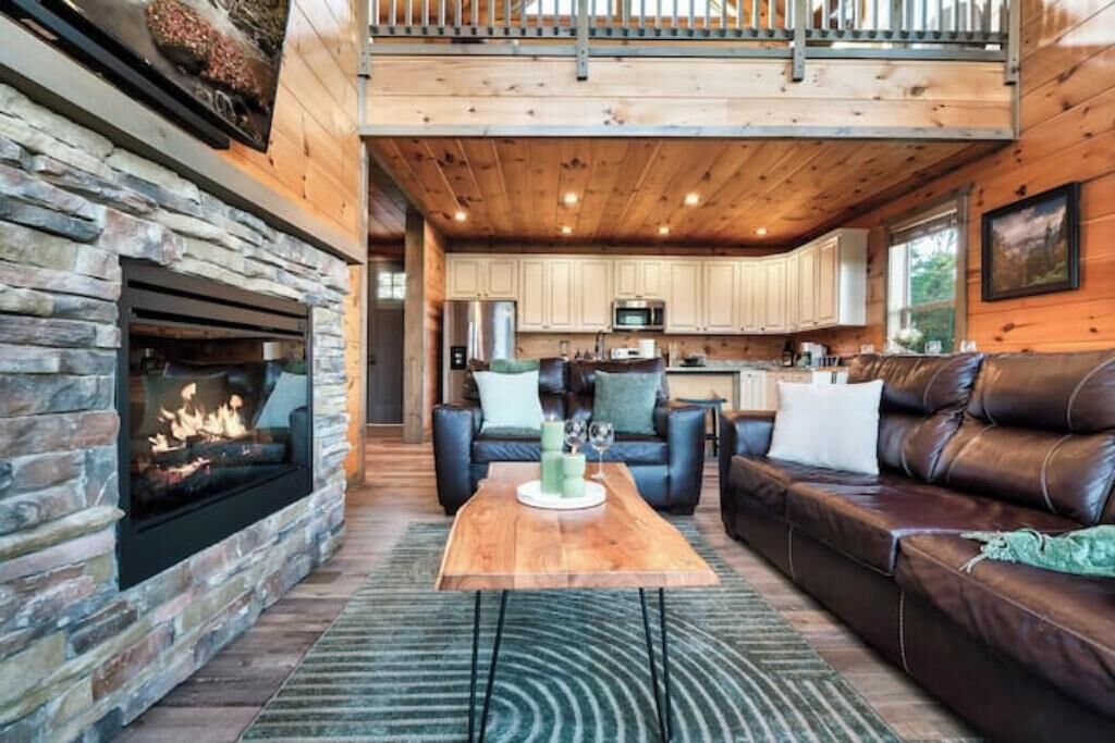 A cozy living room with a fireplace, leather sofa, and a wooden coffee table.