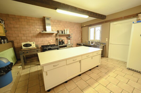 A kitchen with a large island, a stove, a microwave, and a sink. - A L'OREE DU BOIS, 500 m² vacation rental for 15 people with a pool and hot tub (Signy-l'Abbaye)