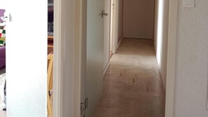 A hallway with a light wooden floor, white walls, and a hanging woven light fixture. - Beautiful bright apartment, exceptional view (Vallauris)
