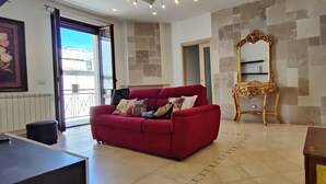 A living room with a red sofa, a gold ornate mirror, and a tiled floor.