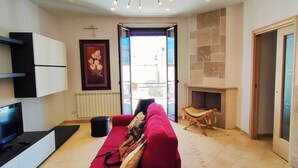 A living room with a TV, red sofa, fireplace, and a stone wall.