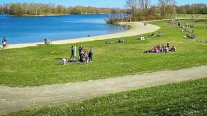 Un parc avec un lac, des espaces verts et un sentier pédestre.
