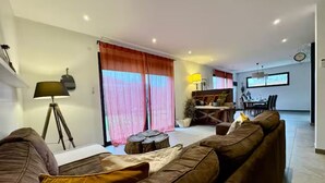 Un salon avec un canapé marron, une lampe et un coin repas comprenant une table et des chaises.