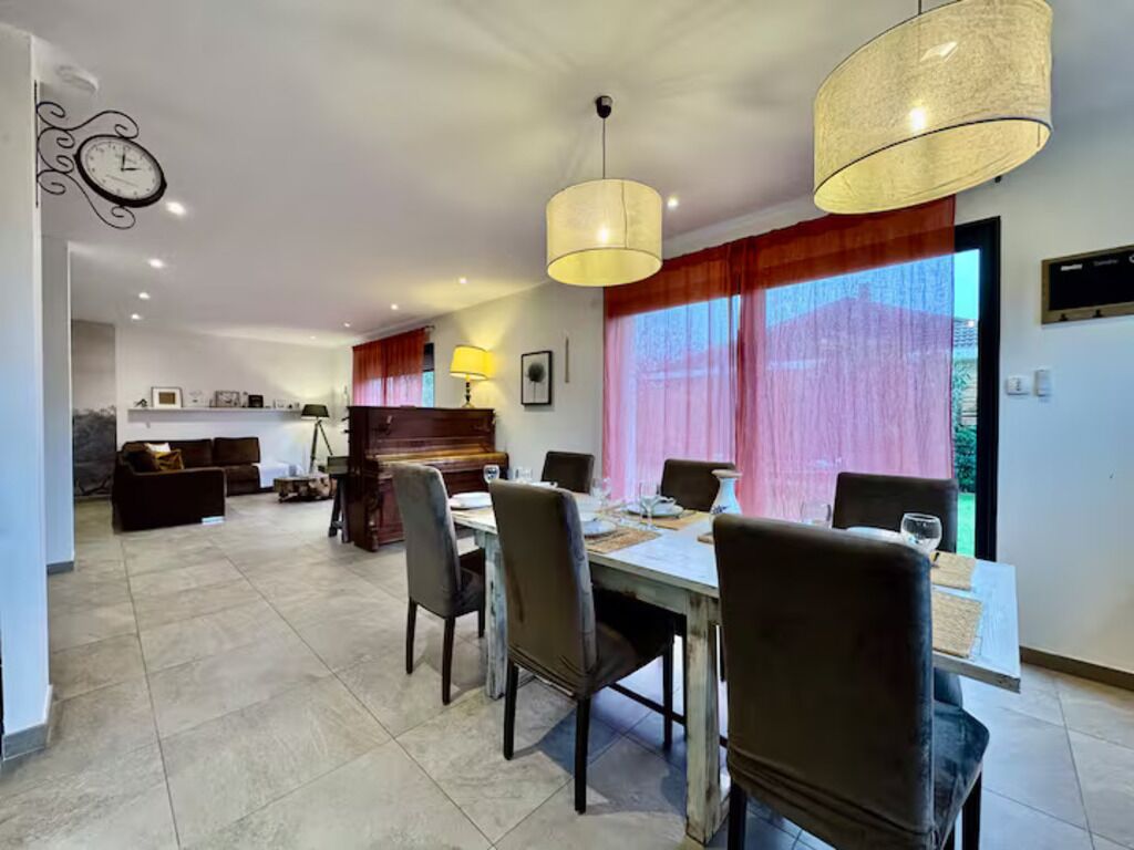 A dining area with a table set for four, chairs, and pendant lighting.