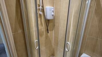 A glass-enclosed shower with a toilet to the right.