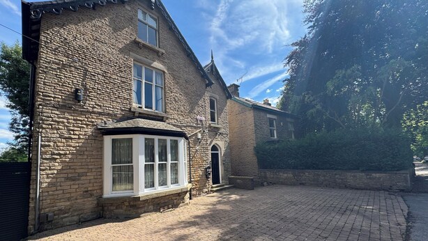 A stone building with a large bay window, a door, and a small porch area.
