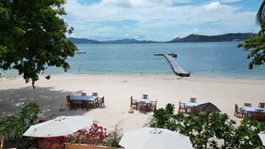 A beachside restaurant with outdoor seating, a wooden deck, and a view of the sea and mountains. -  Cruiser Island Resort by Swiss-Belhotel (Koh Lon)