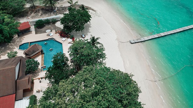 An aerial view of a beach resort with a swimming pool, beach, and a pier. -  Cruiser Island Resort by Swiss-Belhotel (Koh Lon)