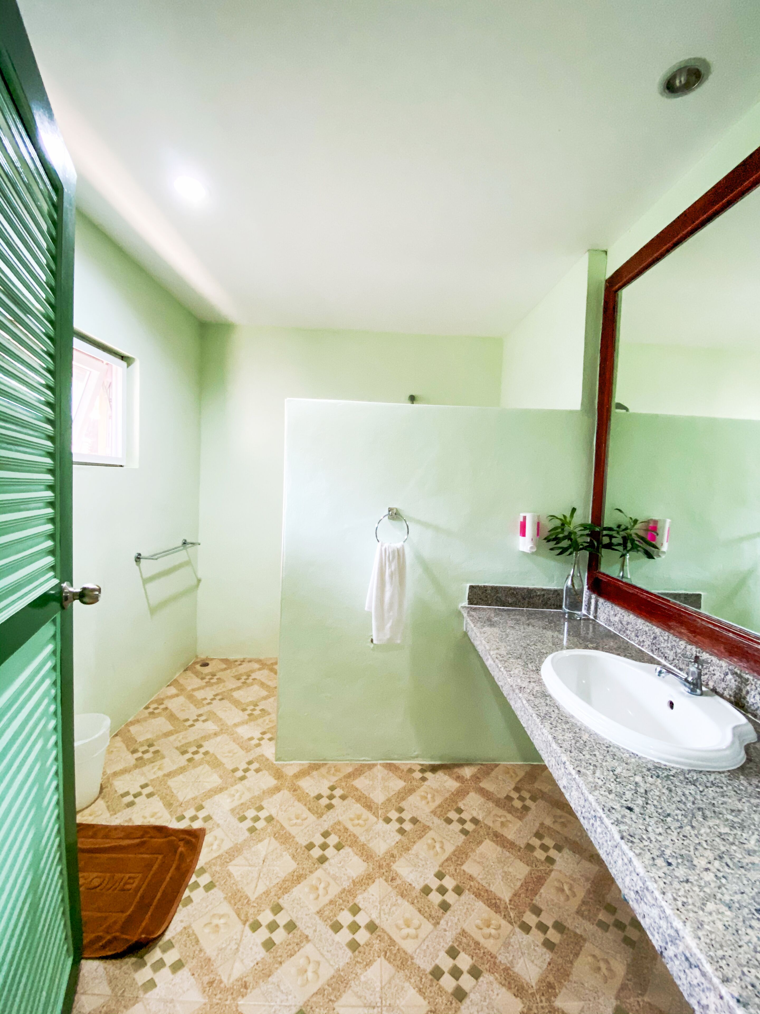 A bathroom with a sink, mirror, towel rack, and patterned floor.