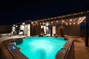A hot tub with a blue light, surrounded by outdoor seating and a covered patio area. - The Lighthouse: Spacious 4-Bedroom Home with Hot Tub, 8 minutes from Joshua Tree (Yucca Valley)