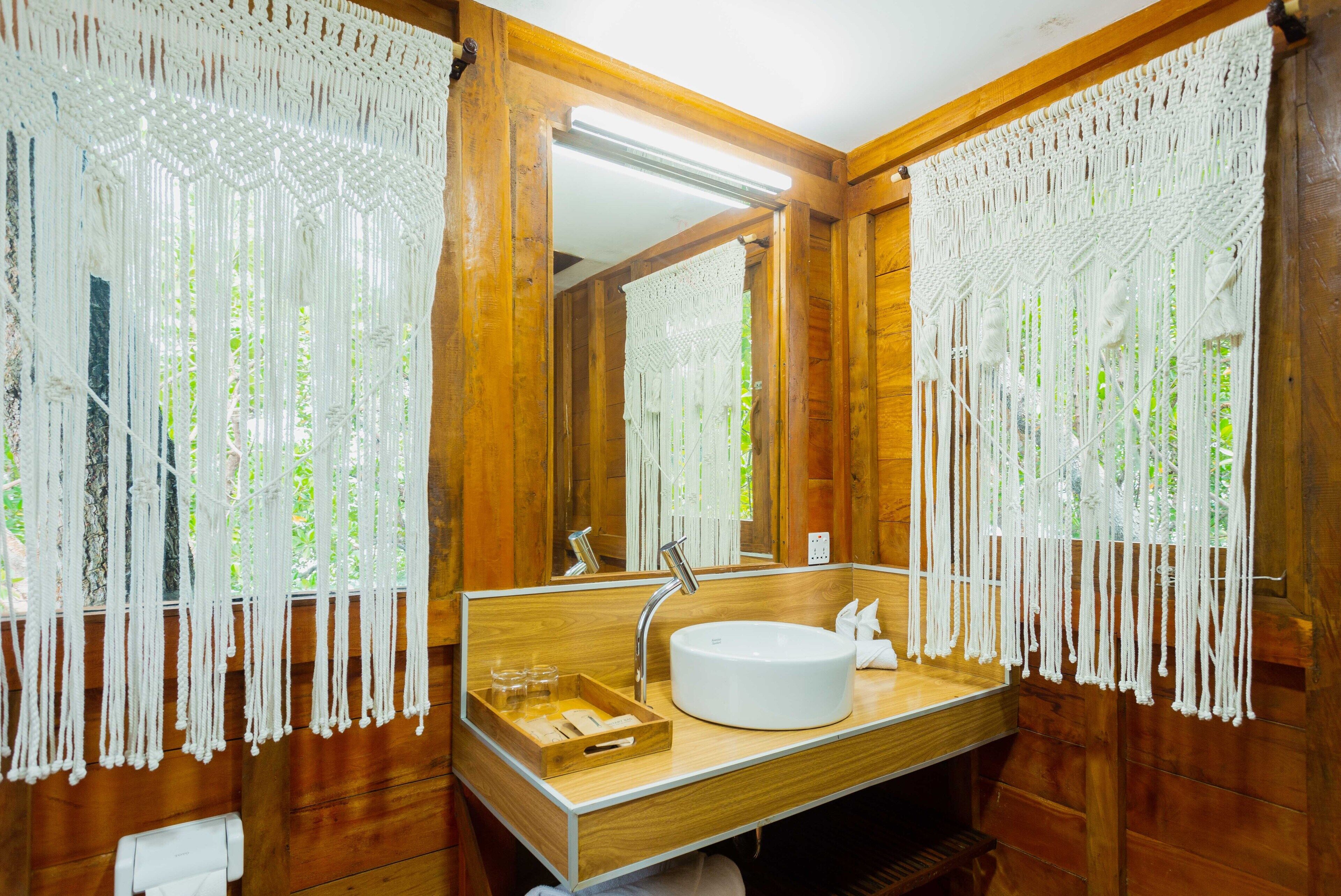 A wooden bathroom with a round sink, wooden vanity, and a mirror.
