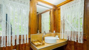 A wooden bathroom with a round sink, wooden vanity, and a mirror.