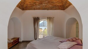 Une chambre à coucher avec un grand lit, une commode en bois et une vue sur une montagne et un lac, visible par la fenêtre.