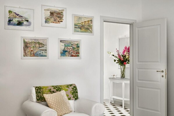 Une pièce avec un canapé blanc, une porte blanche et quatre tableaux encadrés accrochés au mur.