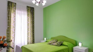 A room with a bed, two bedside tables, a chair, a vase with flowers, and a chandelier. - Central apartment Stella House (Massa Lubrense)