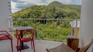 A balcony with a table, chairs, and a view of a lush green landscape.