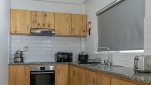 A modern kitchen with wooden cabinets, stainless steel appliances, and a large window.
