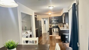 Una cocina moderna con electrodomésticos de acero inoxidable, un comedor con mesa de madera y un área de lavandería con lavadora.