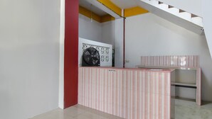 Zona de recepción con mostrador a rayas, un ventilador y una escalera con detalles amarillos.