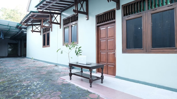 A traditional building with a tiled courtyard, wooden doors, and a table with a plant. - SPOT ON 92068 Pudja Kesuma Homestay Syariah Yogyakarta (Sleman)