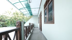 A covered corridor with a metal railing, large windows, and a view of greenery outside. - SPOT ON 92068 Pudja Kesuma Homestay Syariah Yogyakarta (Sleman)