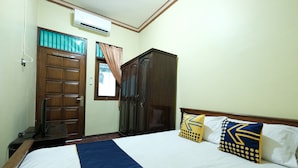 A bedroom with a bed, a wardrobe, a desk, and an air conditioning unit. - SPOT ON 92068 Pudja Kesuma Homestay Syariah Yogyakarta (Sleman)