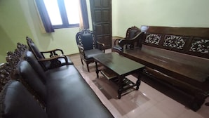 A traditional living room with a sofa, two armchairs, a coffee table, and a wooden cabinet. - SPOT ON 92068 Pudja Kesuma Homestay Syariah Yogyakarta (Sleman)