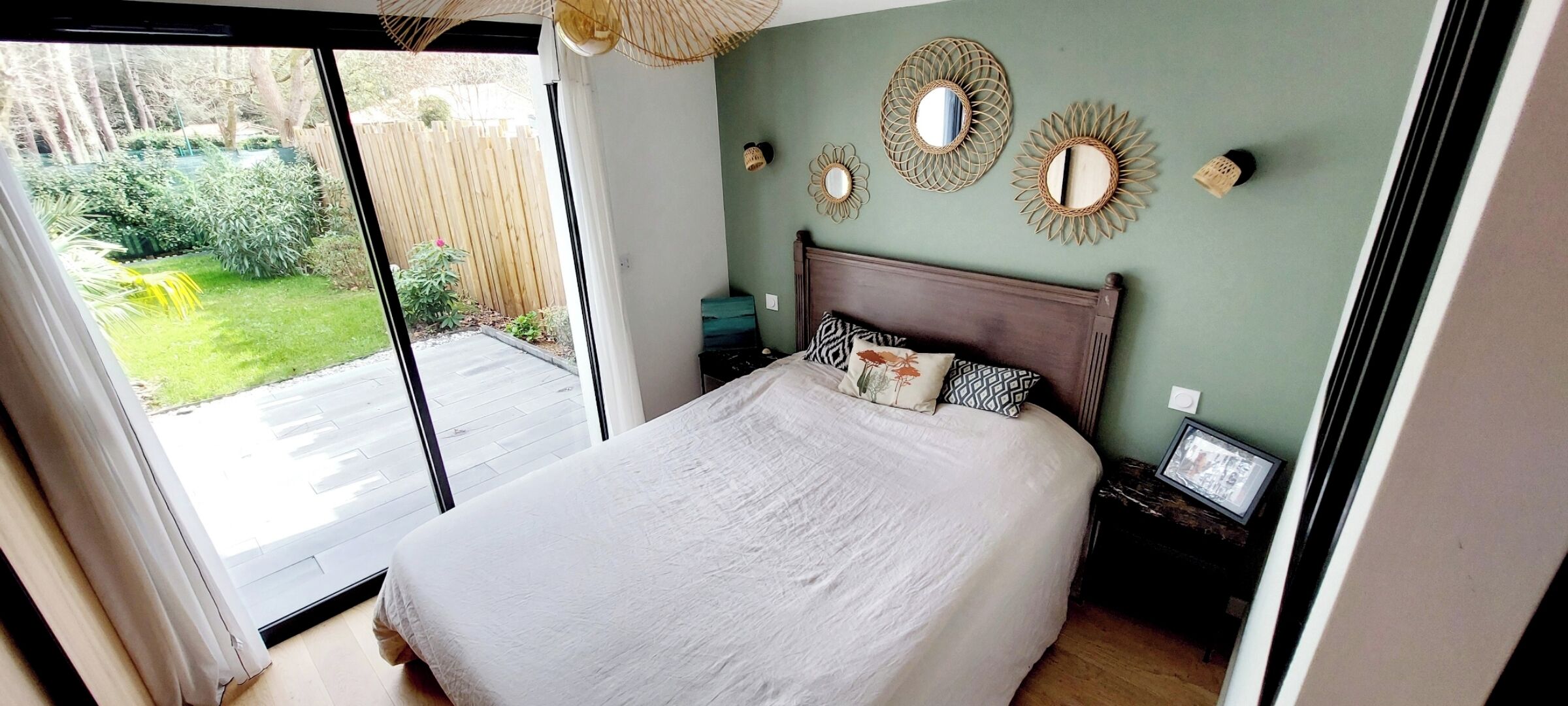 A bedroom with a bed, a nightstand, and a wall-mounted mirror.