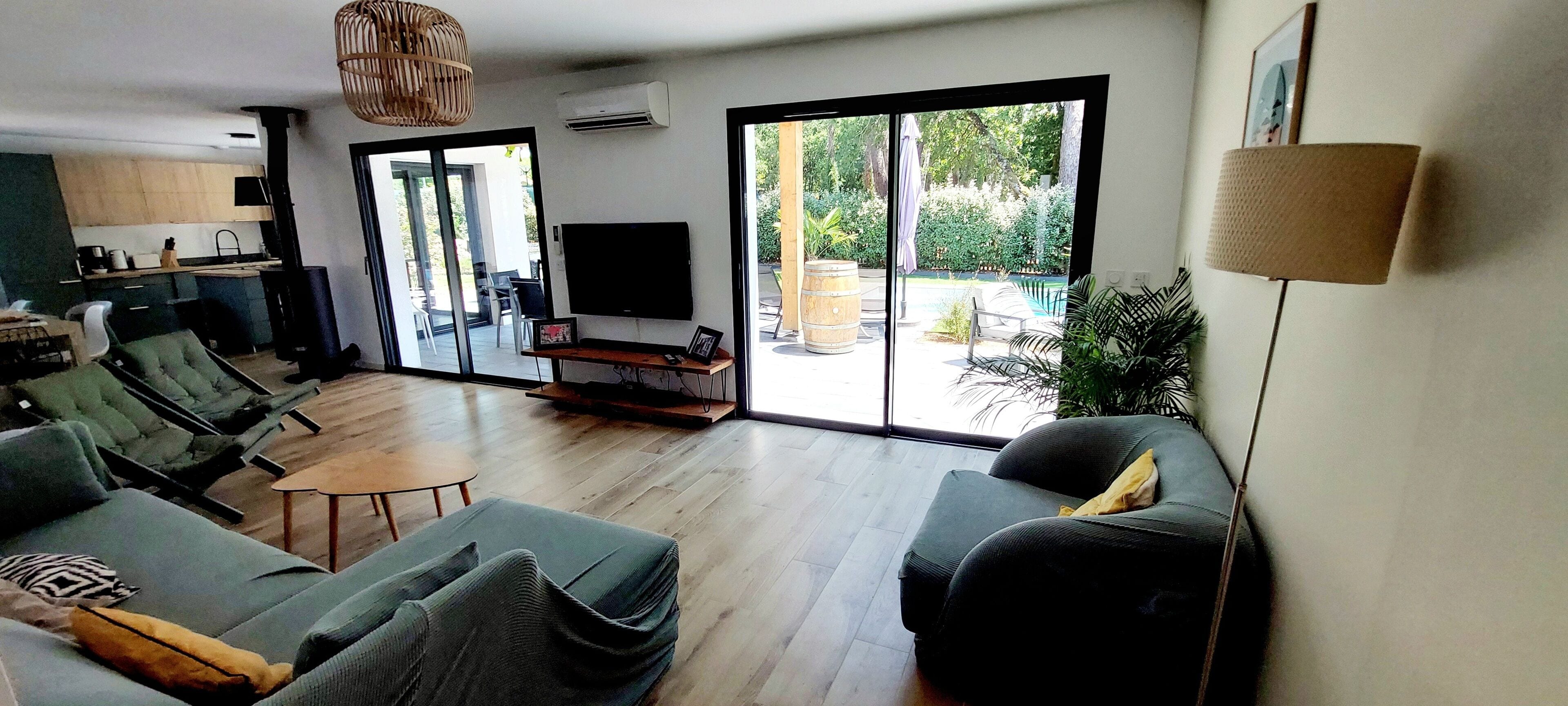 Een moderne woonkamer met een bank, televisie en een schuifdeur naar een terras.