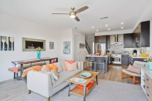 A modern apartment with a living room, dining area, and kitchen.