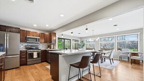 A modern kitchen with wooden cabinets, stainless steel appliances, and a large island with bar stools.