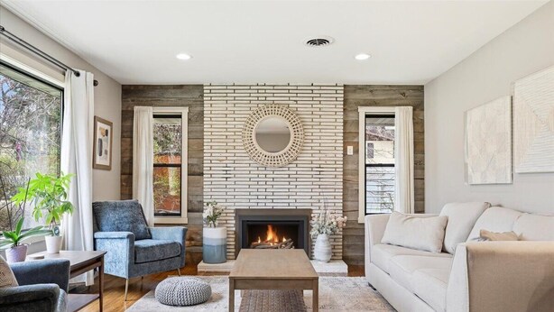 A living room with a fireplace, a round mirror, and a sofa.