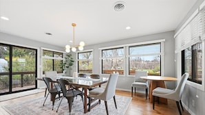 A modern dining area with a round table, chairs, and a patterned rug.