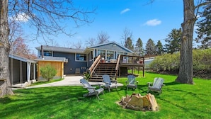 A two-story house with a deck, outdoor seating, and a fire pit.