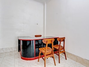A small room with a corner table and two wooden chairs. - OYO 92166 Nirwana Inn Syariah (Sewon)