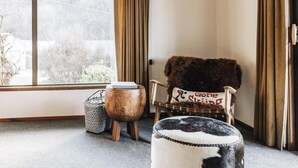 A room with a wooden ceiling, large windows, a fur chair, and a cowhide ottoman. - Charming House With all the Home Comforts (Arrowtown)