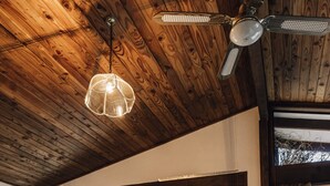 A cozy living room with a wooden ceiling, a fireplace, a sofa, and a view of a mountain. - Charming House With all the Home Comforts (Arrowtown)
