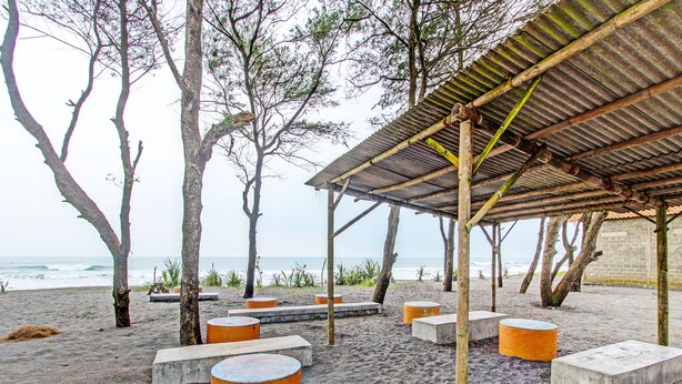 A beach with a covered seating area and concrete planters. - Hotel O Sari Laut (Temon)