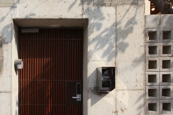 A metal door with a vertical handle and a small window above it.