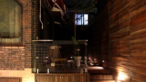 Un área de estar moderna al aire libre con bancos de madera y una partición de vidrio.
