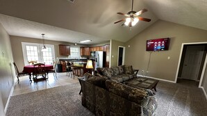 A spacious living area with a large couch, a dining table with chairs, and a kitchen in the background. - Life is Good in Mayflower (Mayflower)