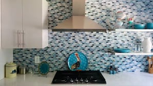 A modern kitchen with a tiled backsplash, stainless steel appliances, and a variety of kitchenware.