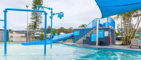 A swimming pool with a blue slide and a lifeguard station.
