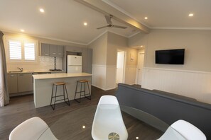 A modern kitchen with a central island, bar stools, and a ceiling fan. - NRMA Forster Tuncurry Holiday Park (Tuncurry)