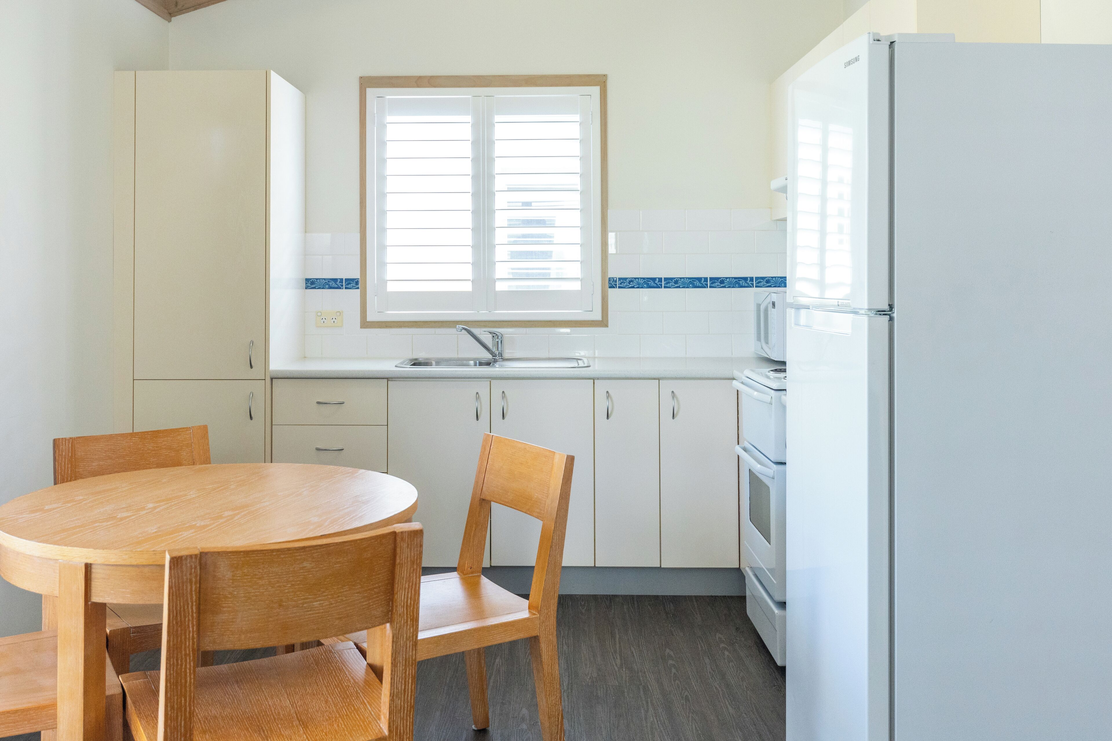 A kitchen with white cabinets, a wooden dining table, and chairs.
