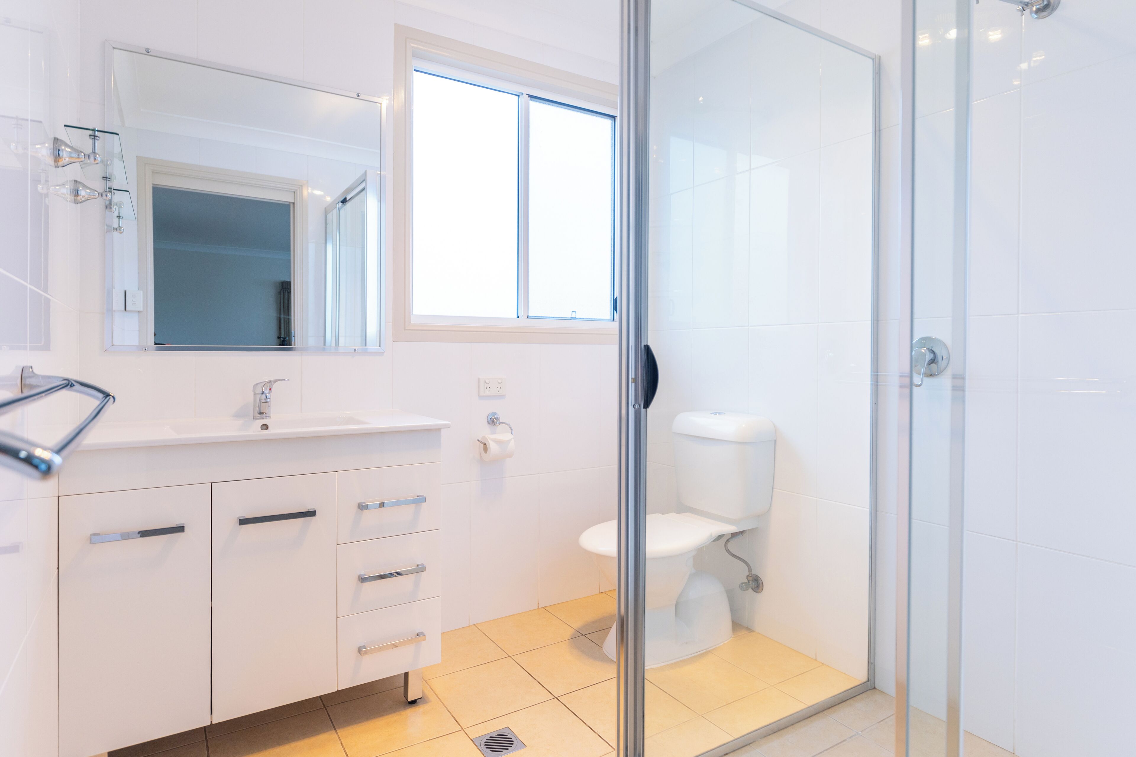 Et moderne badeværelse med et glasbadekabine, en hvid vask og et toilet.